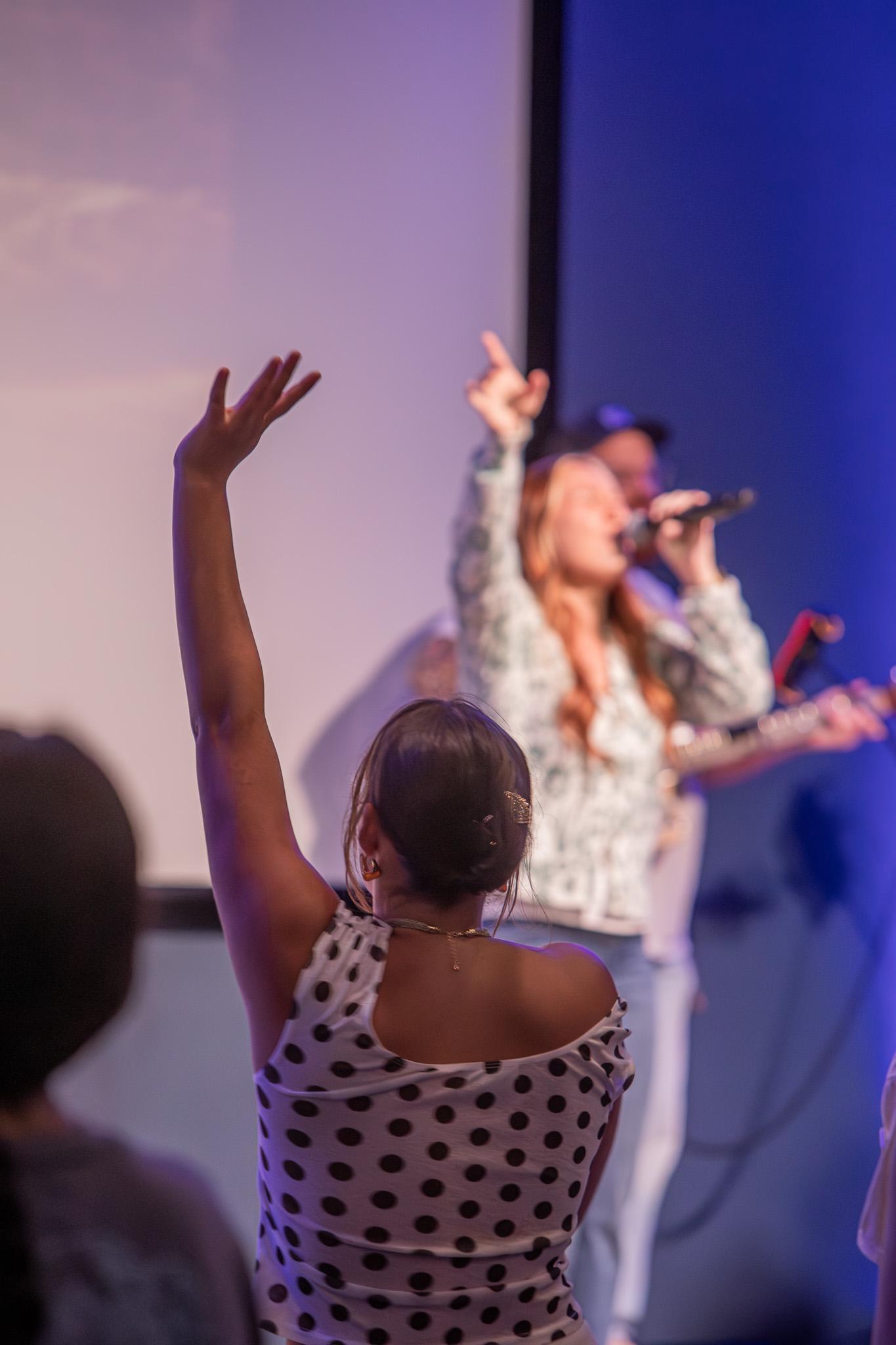 A worshipper raising a hand while the Good News Co. team sings.